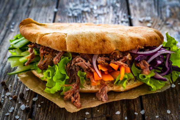 istock Pita - big sandwich with pulled beef and fresh vegetables on wooden table 2012679983