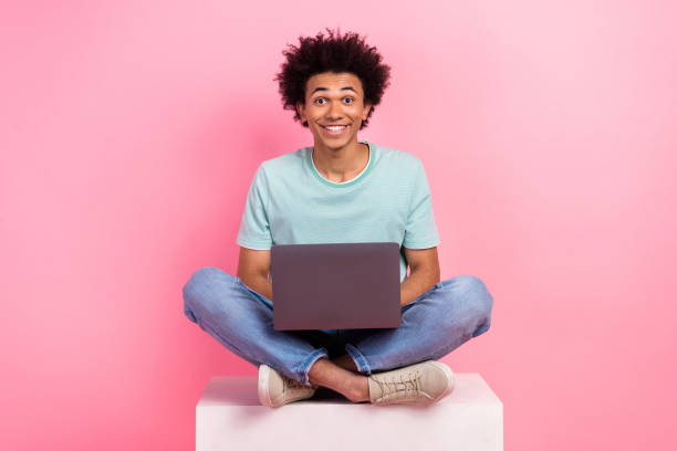 istock Full length photo of handsome young male sit white cube remote work netbook dressed stylish blue garment isolated on pink color background 2012684955