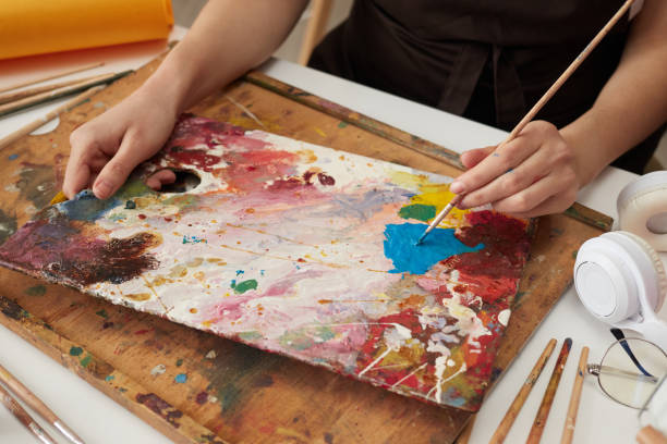istock Unrecognizable woman painter wearing brown apron in art studio drawing picture using colorful paints drawing abstract work of art closeup hands with paintbrush 2012713015