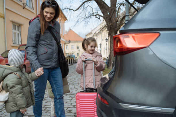 istock Kids on road trip with mother, loading baggage in the car trunk 2012717513