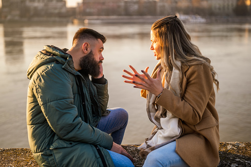 Couple having conflict and  they are arguing while sitting outdoor.