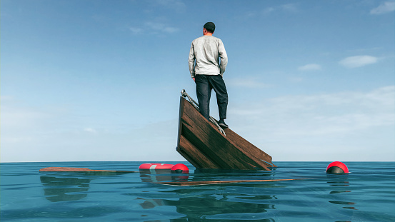 Man stands atop the remnants of a submerged boat, gazing into the horizon over a calm sea, encapsulating a moment of reflective isolation. Concept of failure.