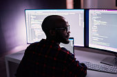 Cyber security, black man and code reflection in eyewear, hacking and software update in office. African American male employee, programmer or IT specialist with glasses, focus and cloud computing