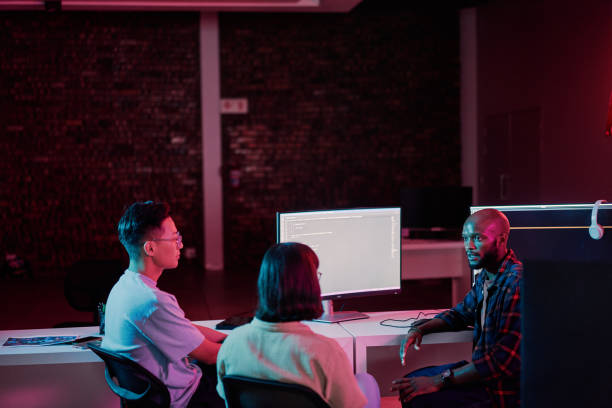 istock Business people, talking or planning teamwork in night office of software development, cybersecurity or database safety. Programmer, developer or engineer on neon technology for coding diversity idea 2012746937
