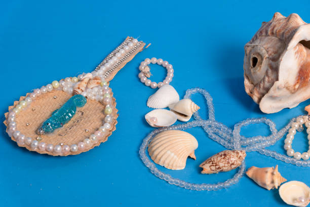 Several sea shells, necklaces and mirror scattered on the blue studio floor. Tribute to iemanja.