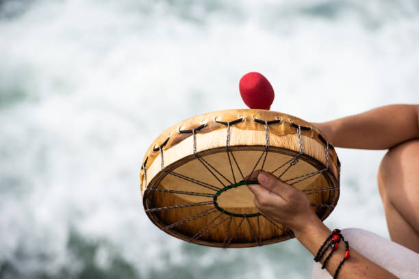 Hands playing a drum in front of the sea waters. Tribute to iemanja.