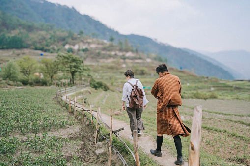 Bhutanese tour guide and Asian female tourist walking at rural area paddy field in Bhutan