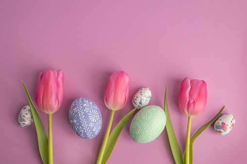 Three purple tulips with Easter eggs on a purple background.