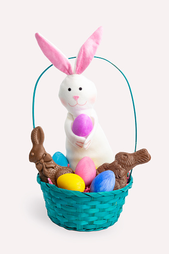A small Easter basket filed with eggs, chocolate and a toy rabbit isolated on a white background.
