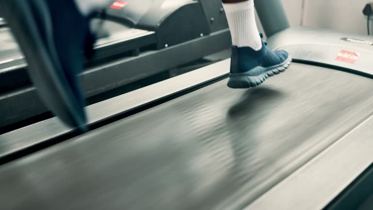 Person, shoes and running on treadmill for cardio, exercise or indoor training at gym. Closeup of runner or athlete legs in fitness on stationary machine or equipment for weight loss at health club