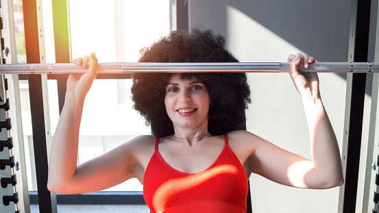 Portrait of a middle-aged woman lifting weights gym during training.