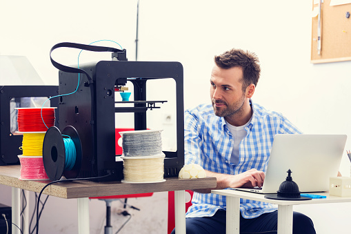 Man working in a 3d printer office, watching at 3d printout.