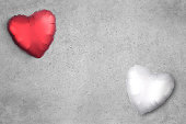 White and red heart balloons on a cement background