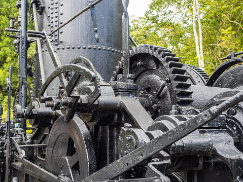 An abandon vintage train steam engine with full connections of gears, shafts, and rods.