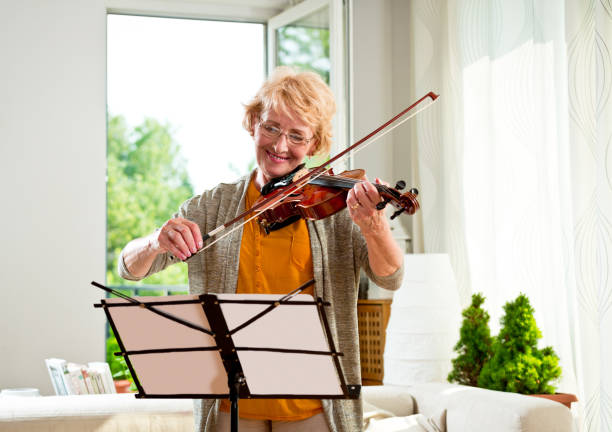 istock Senior woman playing violin at home 2012815077