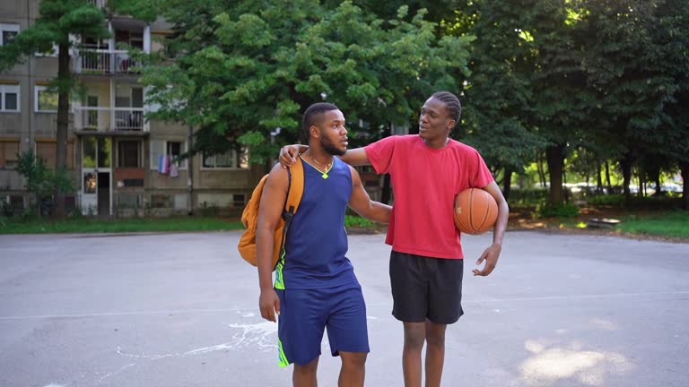 Two black boys meeting on a basketball the court