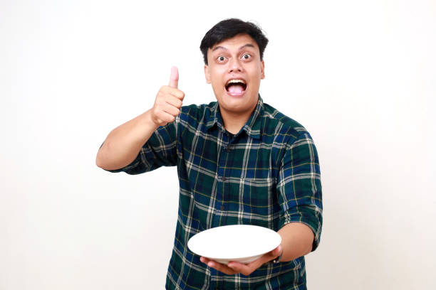 istock Young asian man showing happy expression and thumbs up while holding an empty plate 2012829825