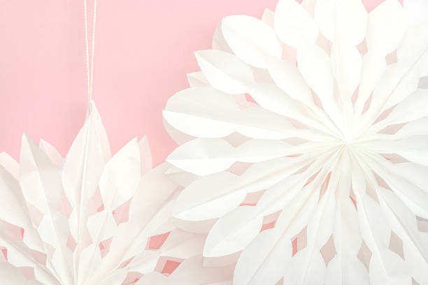 Traditional paper 3D snowflakes on pastel pink background. Winter handmade, DIY activity. Festive elements for decorating home to Christmas holiday. Place for text