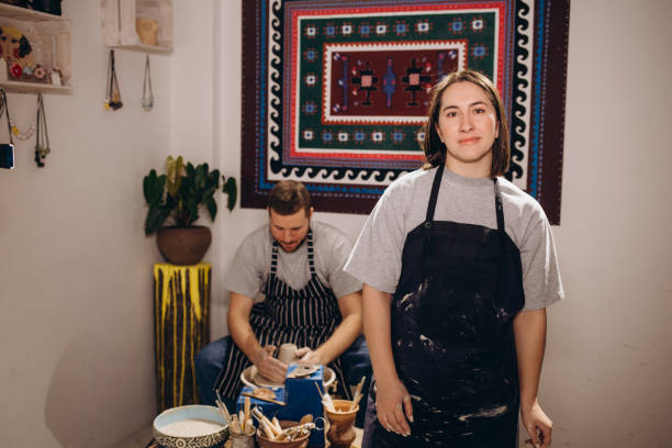 istock handsome man and happy woman couple in love working on potter wheel while at pottery workshop. husband and wife in the kraft creative studio,young family business shop sculpts pot from clay. 2012843821