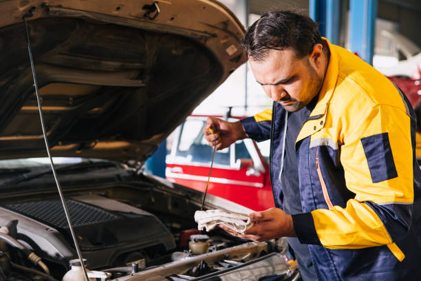 Garage auto mechanic worker working check engine oil level stick in car service center, Indian professional male working