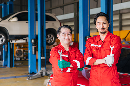 Portrait Asian Japanese male mechanic workers team in auto service workshop car maintenance center replace fix auto engine part