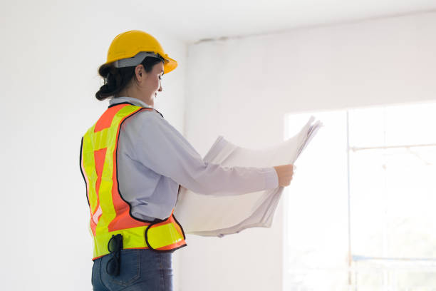 istock Smart young working women construction engineer builder caucasian female architect looking floor plan in under construction site building project management. 2012850347