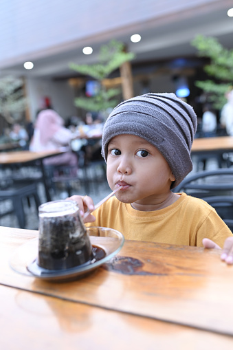 Asian child drinking unique coffee with an upside down glass in Aceh, Indonesia