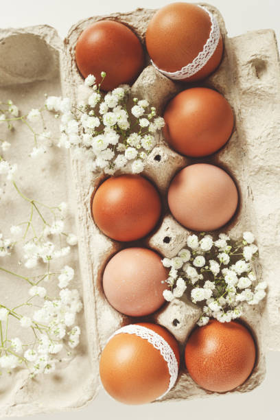 istock Easter eggs and white blooming flowers in carton package on light background, retro toned. Easter holiday concept, Closeup handmade chicken eggs decorated lace, symbol springtime holiday 2012883561