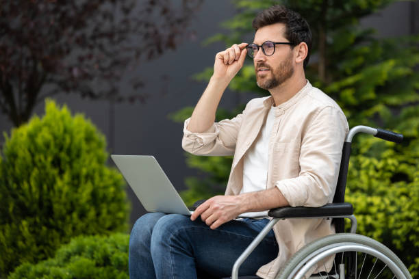 istock Young bearded man in a wheelchair working on laptop 2012886805