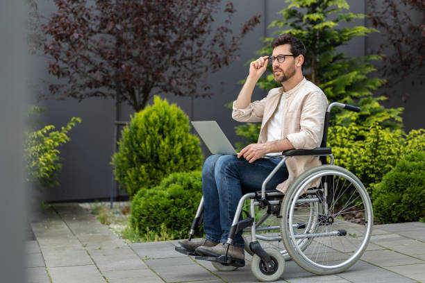 istock Young bearded man in a wheelchair working on laptop 2012886806