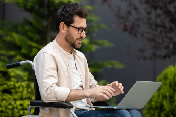 istock Young bearded man in a wheelchair working on laptop 2012886807
