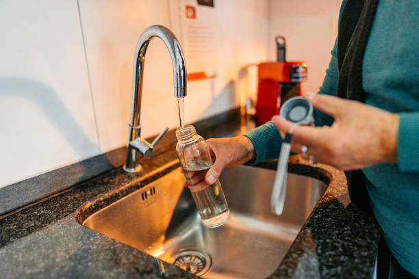 istock Senior Woman Refiling Her Glass Water Bottle With Water 2012887991
