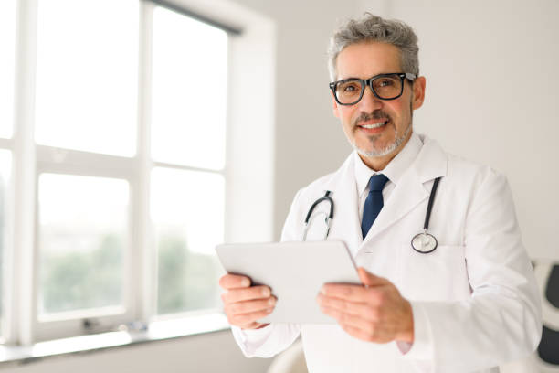 istock Experienced confident senior doctor with grey hair using tablet 2012888022