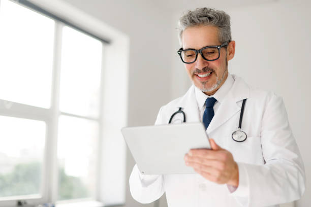 istock Experienced confident senior doctor with grey hair using tablet 2012888023