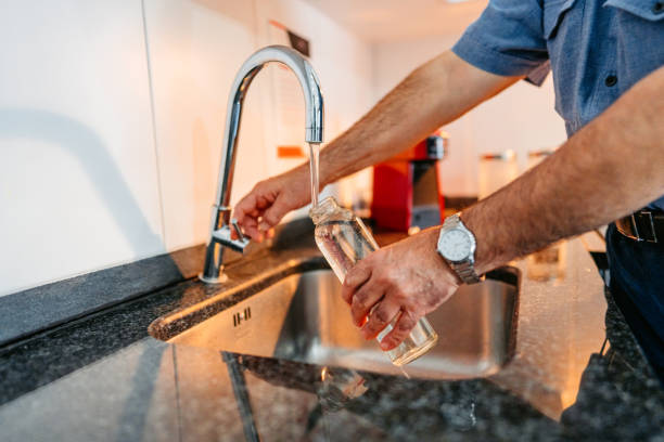 istock Senior Man Refiling His Glass Water Bottle With Water 2012888634
