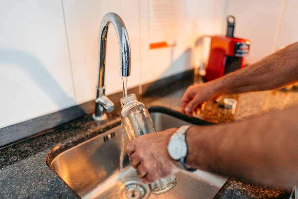 Senior Man Refiling His Glass Water Bottle With Water