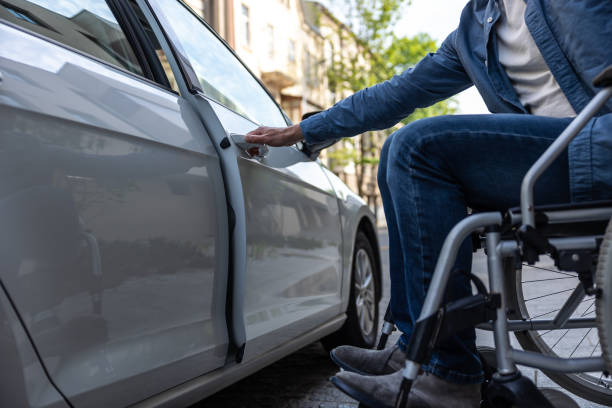 istock Disabled man in a wheelchair getting in a car 2012892080