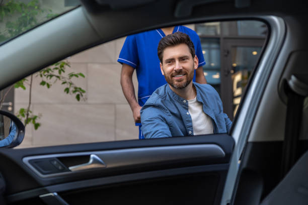 istock Disabled man getting on a car, male nurse helping him 2012892087
