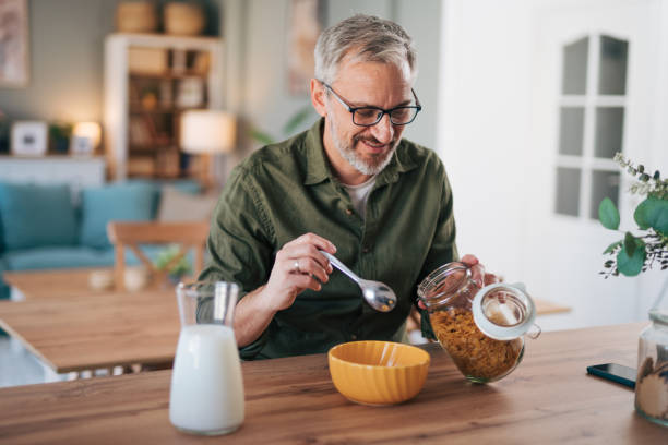 istock An elderly man prepares a healthy breakfast, cornflakes with milk 2012900950