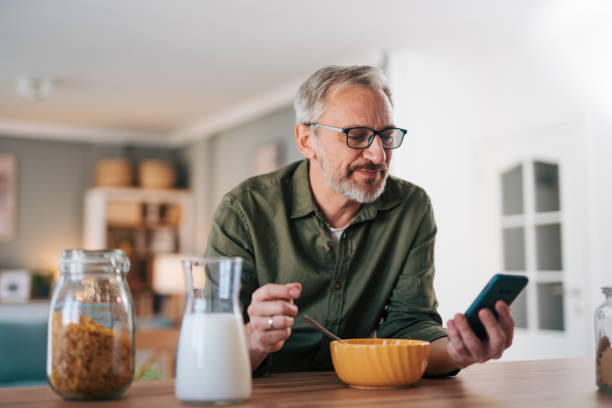 istock Happy senior man reading online newspaper while having breakfast 2012909292