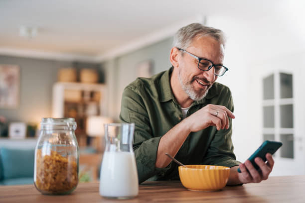 istock Happy senior man reading online newspaper while having breakfast 2012909293