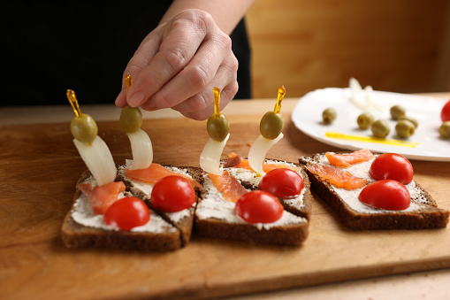 Olives and onions are added to the sandwich. Preparation of canapes with fish and vegetables