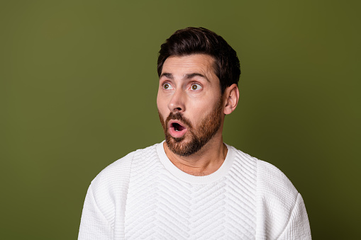 Photo of impressed astonished man wear trendy white clothes look up empty space banner isolated on khaki color background.