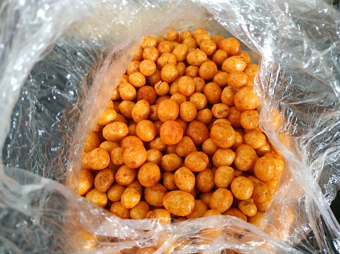 Atomic peanuts are mini ball-shaped snacks made from peanuts coated in tapioca flour and drizzled with a spicy red sauce.