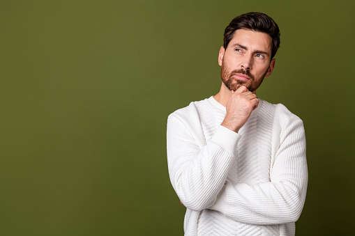 Photo of confident minded man wear stylish white sweater look up empty space banner isolated on khaki color background.
