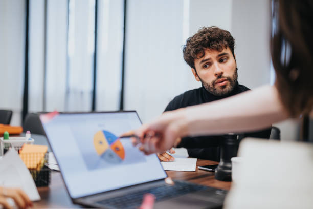 istock Focused businessman in a meeting discussing graphs on a laptop - office setting. 2012940172