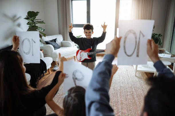 istock Happy little boy is smiling while playing a guitar during a private music learning lesson at home 2012952119