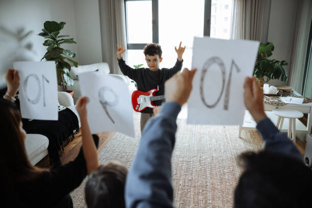 istock Happy little boy is smiling while playing a guitar during a private music learning lesson at home 2012957779