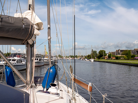 Sailboat with sails down motoring in Zijlroede canal in town of Lemmer, Friesland, Netherlands