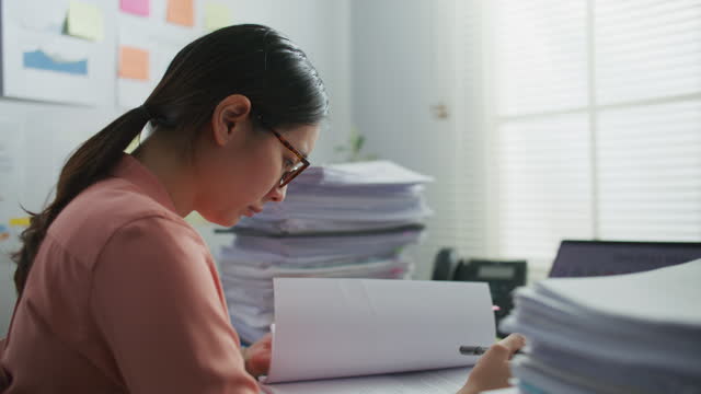Businesswoman working with stacks of document paper on desk, Tracking shot